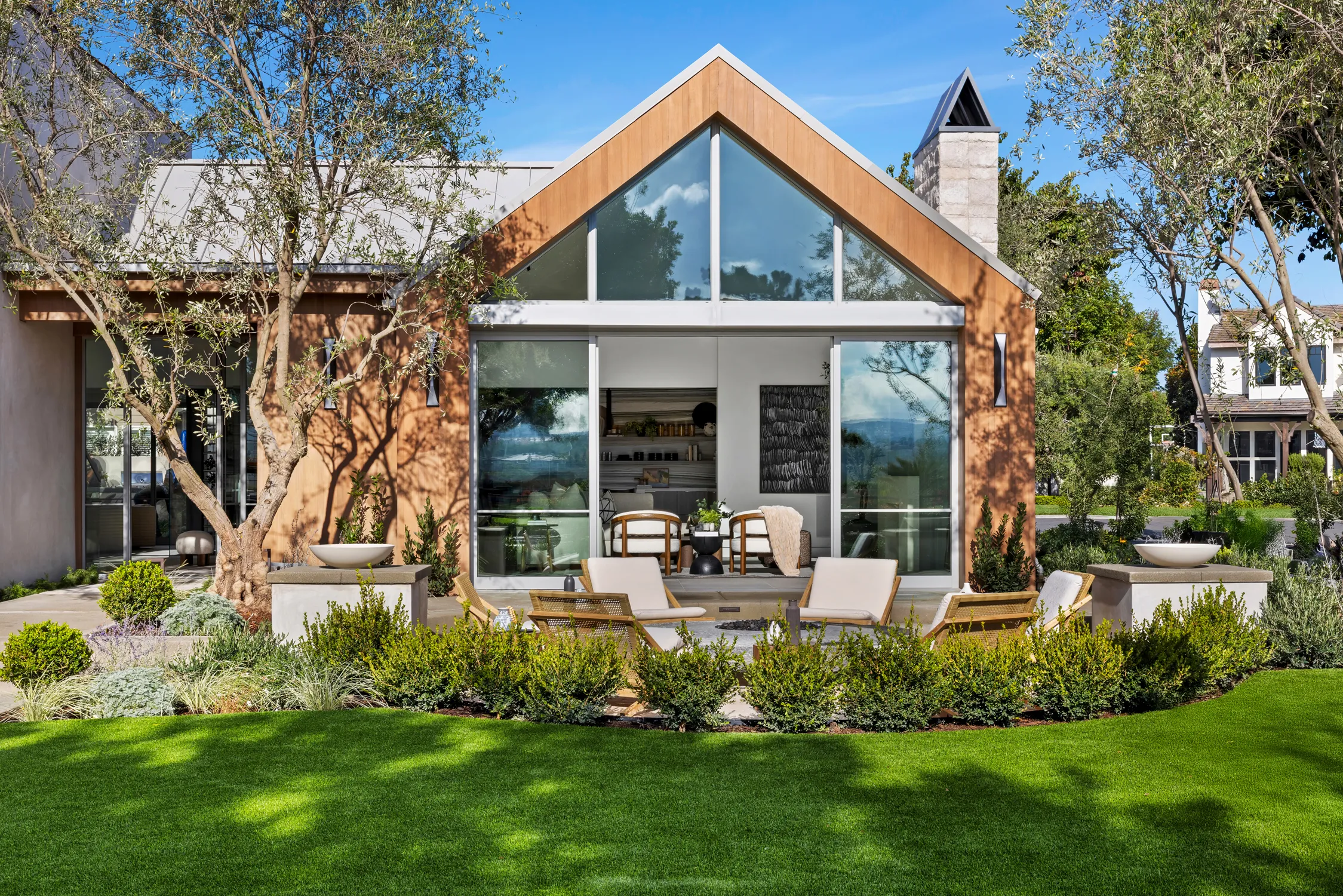 Gabled custom home with glass facade and landscaped front yard